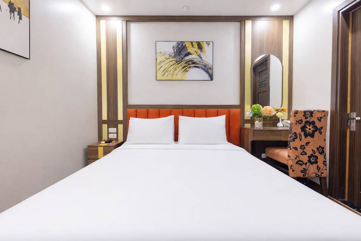 Une chambre d’hôtel avec un grand lit, une table de chevet, une chaise, un miroir et un tableau au mur.