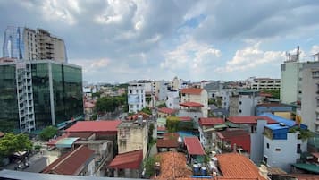 A cityscape with a mix of modern and traditional buildings, including a prominent glass skyscraper and smaller residential structures with red-tiled roofs.