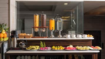 Zona de desballestament per esmorzar amb una màquina de cafè, una presentació de fruita i diferents opcions per esmorzar.