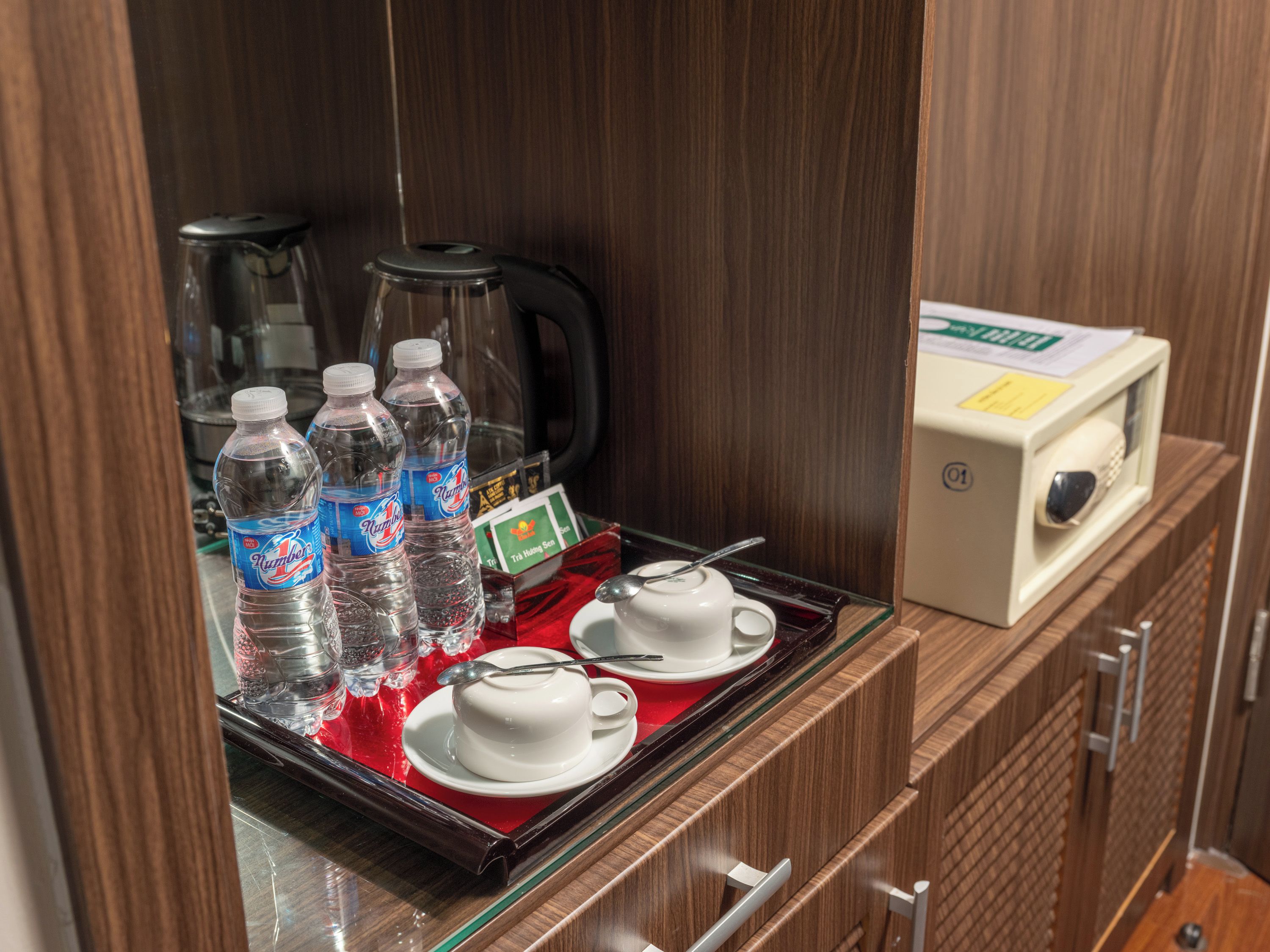 Minibar im Hotelzimmer mit Wasserflaschen, einem Tablett mit Tee und einer Mikrowelle.