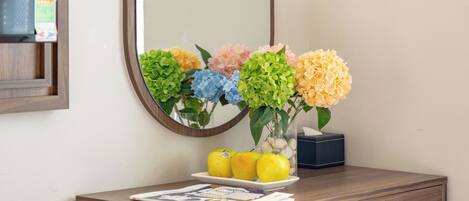 A bathroom vanity with a mirror, a vase of flowers, and a tissue box.