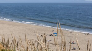 Ein Strand mit Menschen, einem Zelt und Bergen im Hintergrund.
