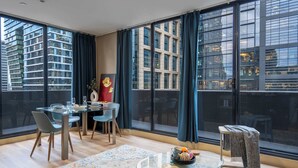 Een moderne eetruimte met een glazen tafel, stoelen en een decoratief vloerkleed.