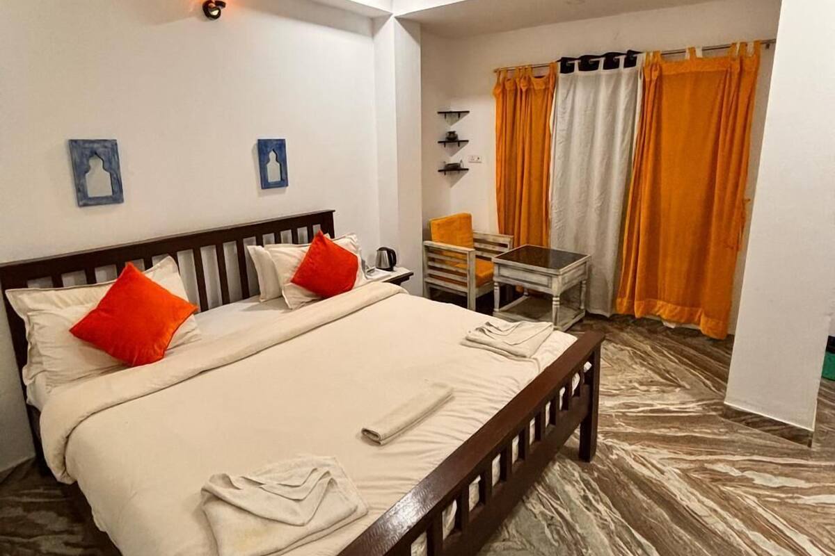 A bedroom with a bed, a desk, a chair, a ceiling fan, and a window with curtains.