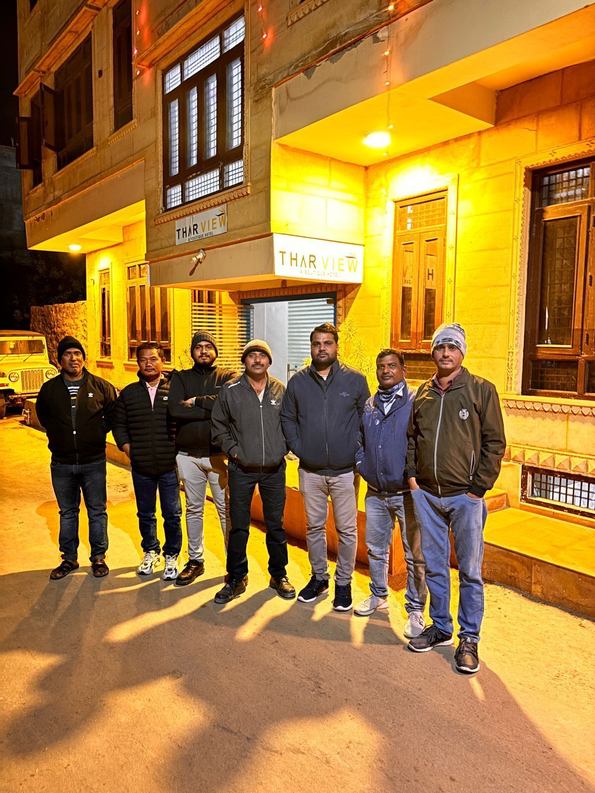 A group of people standing in front of a building with a sign that reads "THAR VIEW."