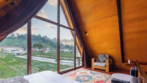 Un dormitorio con una ventana grande, una cama, un sofá pequeño y una mesa redonda.