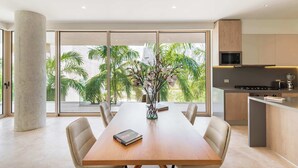 A modern dining area with a wooden table, beige chairs, and a vase with flowers. - Alba Puerto Cancún, Modern Lifestyle with Rooftop Near the Marina (Puerto Cancun)