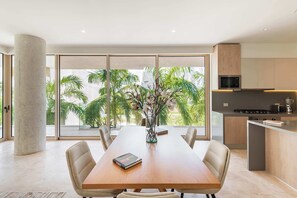 Ein moderner Essbereich mit einem Holztisch, beigen Stühlen und einer Vase mit Blumen.