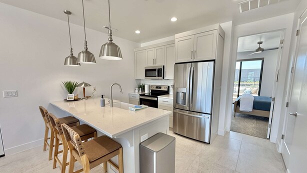 A modern kitchen with a central island, stainless steel appliances, and pendant lighting.