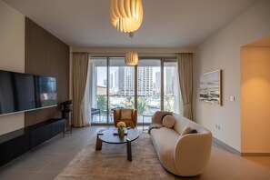 A modern living room with a sofa, a coffee table, a TV, and a large window with a city view.
