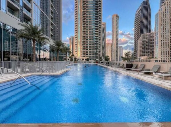A swimming pool surrounded by high-rise buildings, with a clear sky.