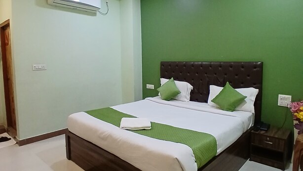 A neatly arranged bedroom with a bed, green walls, a ceiling fan, and an air conditioning unit. - Hotel Mahaveer Paradise Bilaspur (Bilaspur)