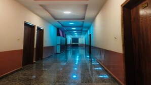 A long, narrow hallway with wooden doors on both sides, a polished marble floor, and recessed lighting. - Hotel Mahaveer Paradise Bilaspur (Bilaspur)