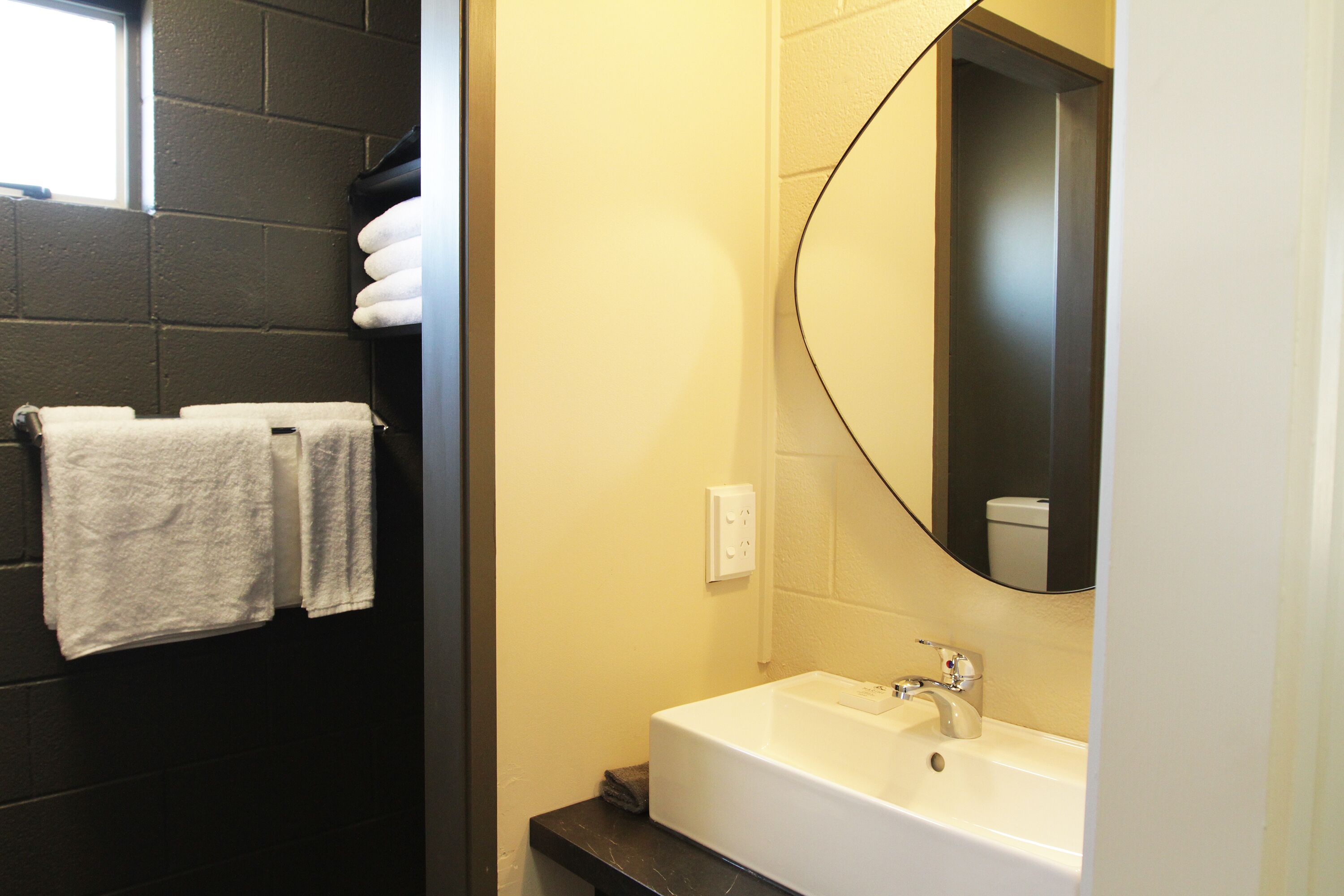 A bathroom with a white sink, a mirror, and two towels hanging on a rack.
