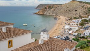 Eine Küstenstadt mit Strand, Häusern mit Terrakotta-Dächern und freiem Blick auf das Meer.