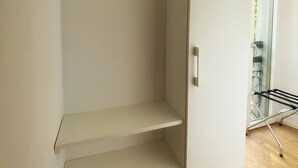 Een moderne, minimalistische kamer met een inbouwkast, inclusief kledingroede en plank.