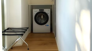 Een wasserette met een voorlader wasmachine, een droogrek en een houten vloer.