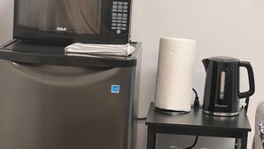 Una kitchenette compacta con microondas, tostadora y un refrigerador pequeño.