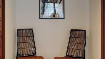 A hallway with two chairs, a framed artwork on the wall, and a hanging light fixture.