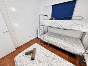 A bunk bed with a patterned bedspread, a rolled-up towel, and a blue headboard.