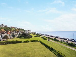 A coastal residential area with terraced houses, a well-maintained lawn, and a parking lot by the sea. - 2 bedroom accommodation in St. Leonards-On-Sea (St. Leonards-On-Sea)