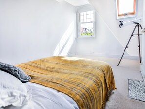 Une chambre à coucher avec un lit, une fenêtre et un trépied.