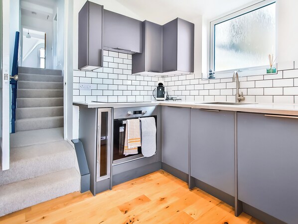 A modern kitchen with grey cabinets, a built-in oven, and a window with a view.