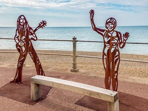 A bench and two metal sculptures by the seaside.