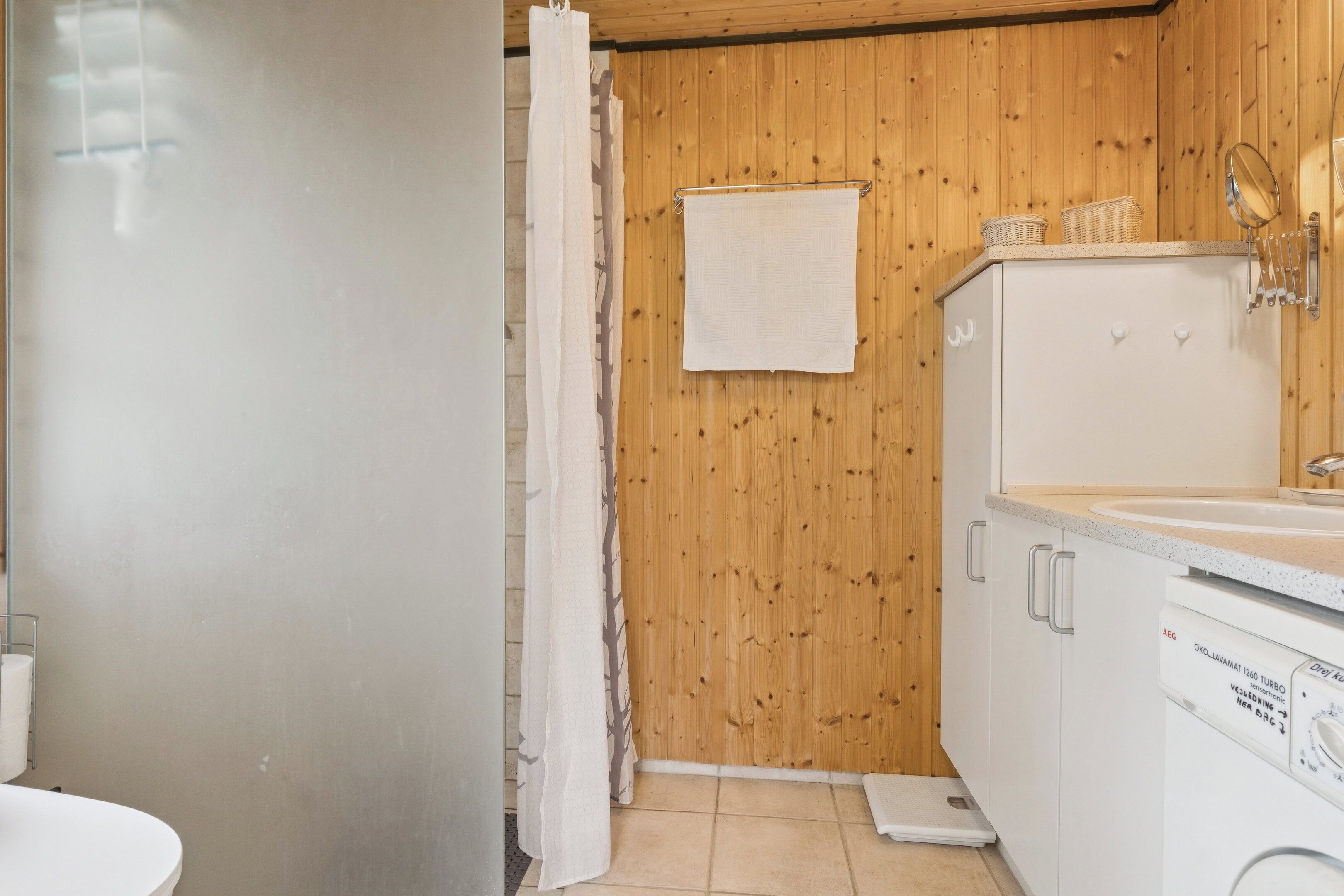 A bathroom with wooden walls, a white sink, a mirror, and a white towel hanging on the wall.