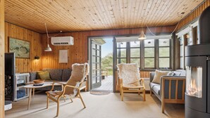 A cozy cabin interior with wooden walls, a sofa, two chairs, a TV, and a fireplace. - Summerhouse in peaceful surroundings (Pandrup)