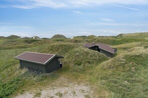 A building with a red roof, surrounded by grassy dunes. - Summerhouse in peaceful surroundings (Pandrup)