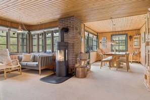 A cozy interior with a fireplace, wooden furniture, and large windows.