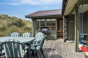A deck with a table and chairs, a grill, and a swing. - Summerhouse in peaceful surroundings (Pandrup)