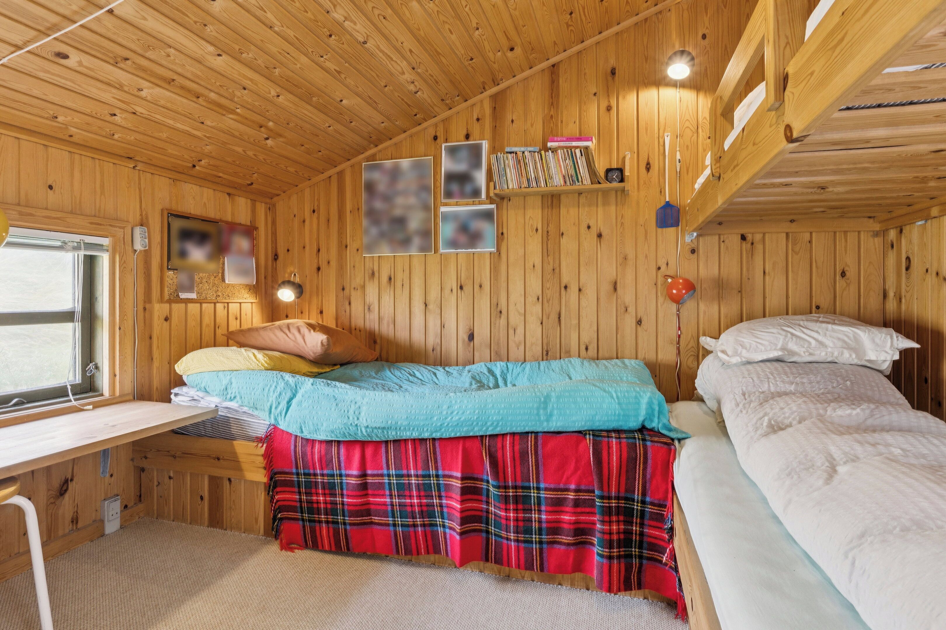 Une chambre dans un chalet en bois, avec des lits superposés, un bureau et une fenêtre.