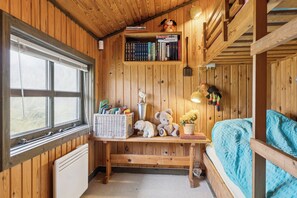 A wooden room with a bed, a desk with books and a teddy bear, a window, and a radiator. - Summerhouse in peaceful surroundings (Pandrup)