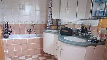 A bathroom with a bathtub, a sink, and a mirror.