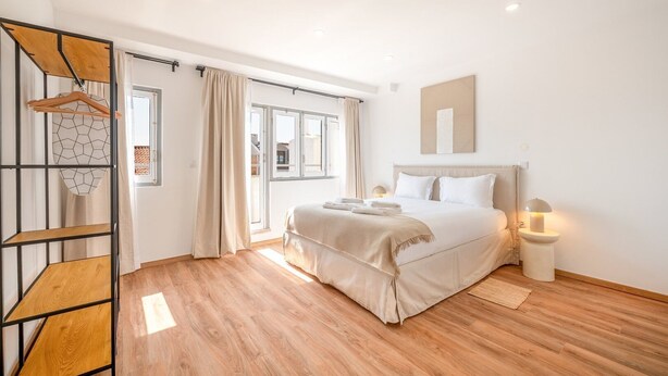 Un dormitorio moderno con una cama, lámparas de noche y suelo de madera.