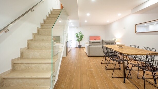 A modern interior with a staircase, a dining area, and a living space.