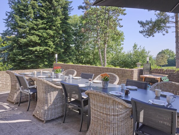An outdoor patio with wicker furniture, a brick wall, and a grill.