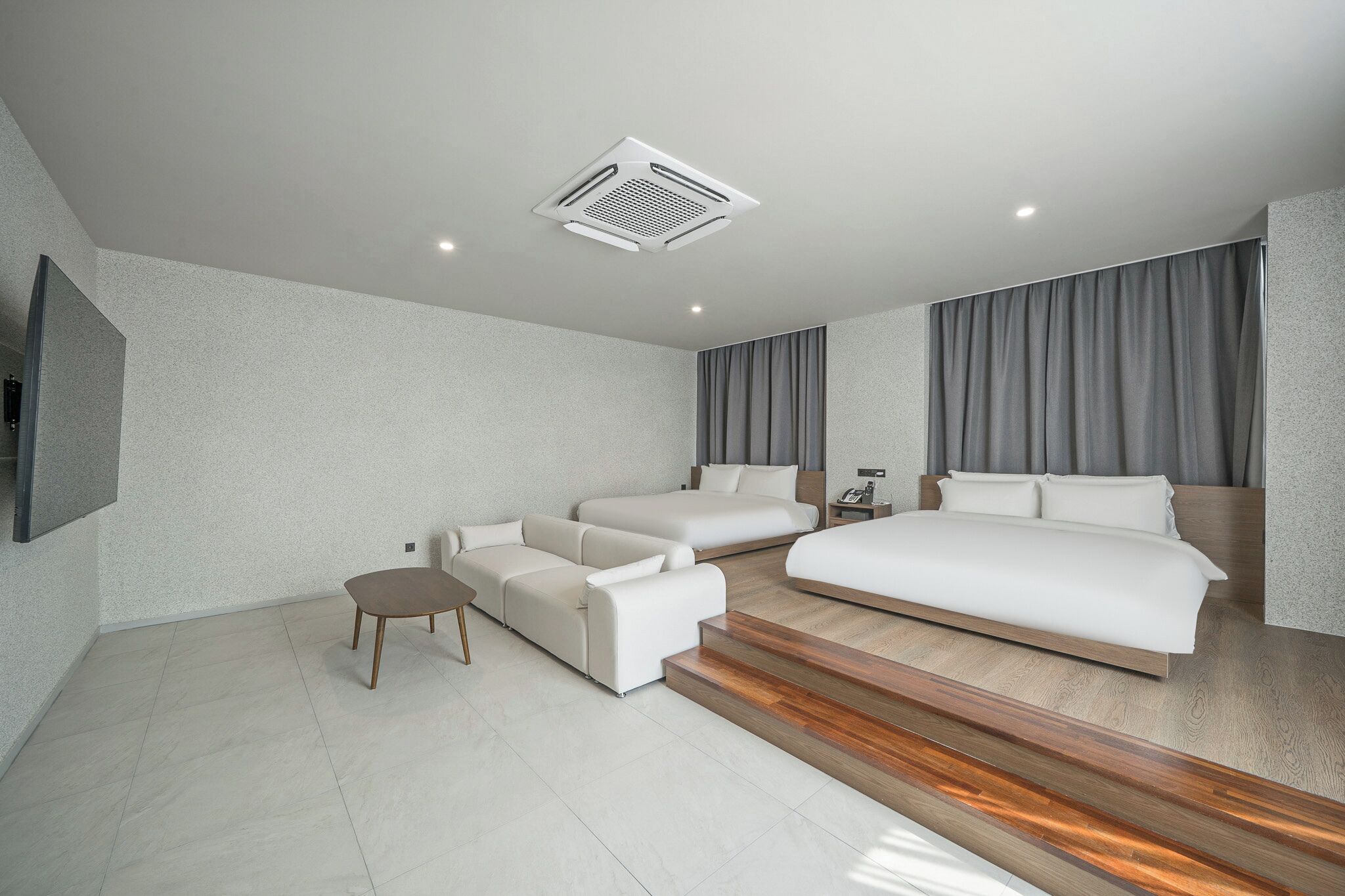 Una habitación de hotel moderna con una cama grande, un sofá, una mesita pequeña y un escritorio empotrado.