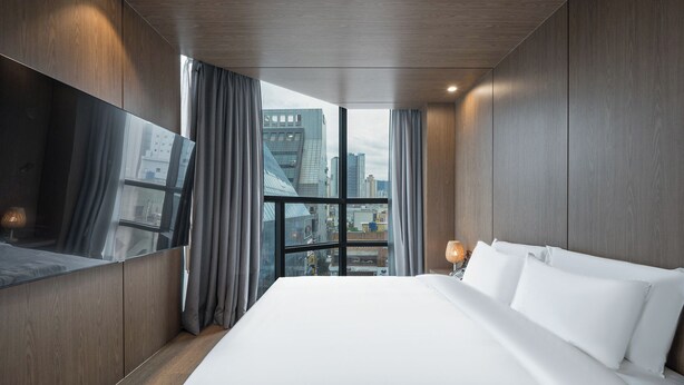 A modern hotel room with a large bed, a city view, and a large mirror. - Giant Hotel (Daegu)