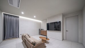 A modern living room with a sofa, a coffee table, a TV, and a cabinet. - Giant Hotel (Daegu)