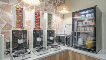 A self-service coffee station with multiple coffee machines and a refrigerator stocked with beverages.
