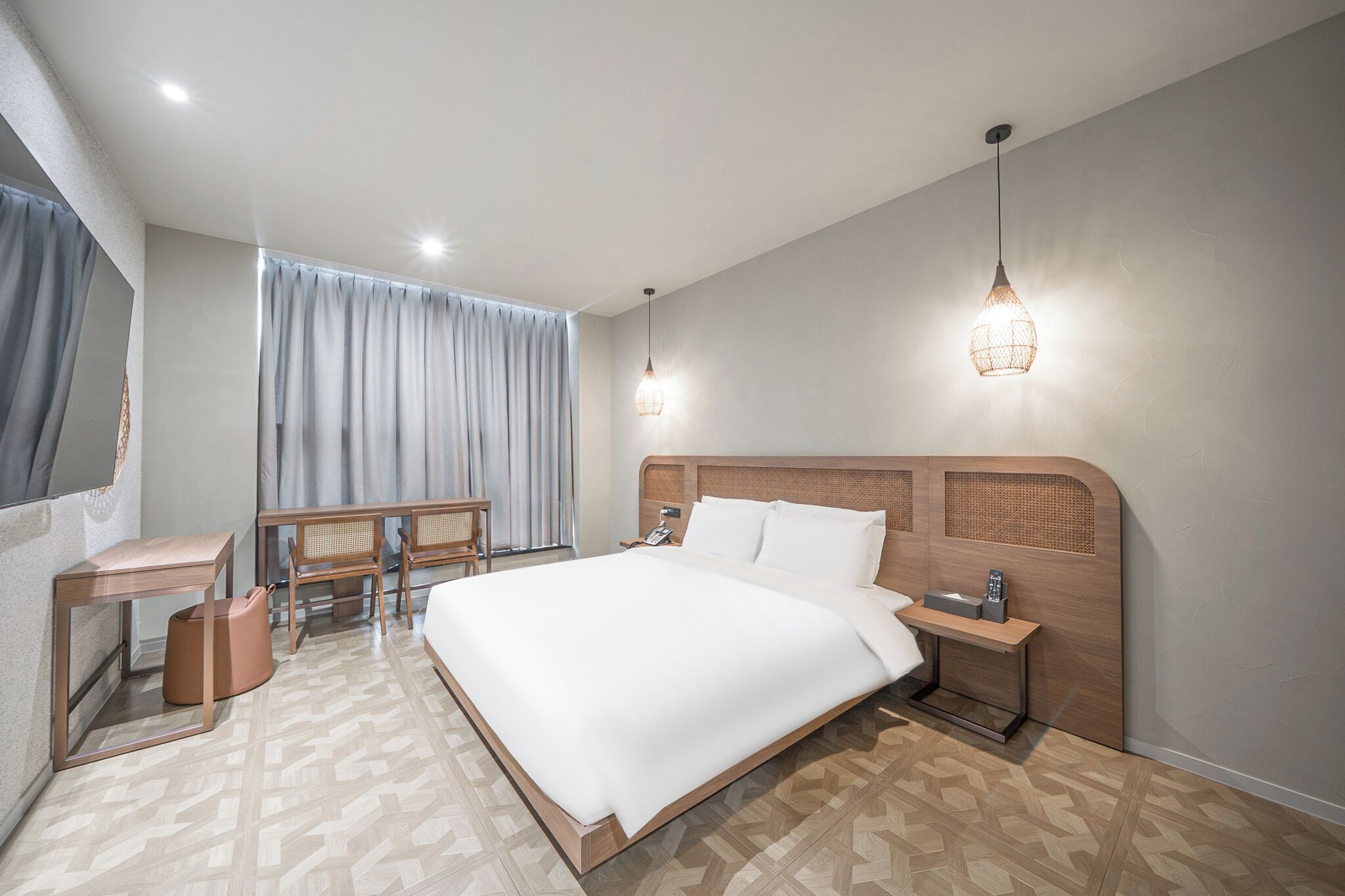 Ein modernes Hotelzimmer mit einem großen Bett, Nachttischen, einem Schreibtisch und einem Stuhl.