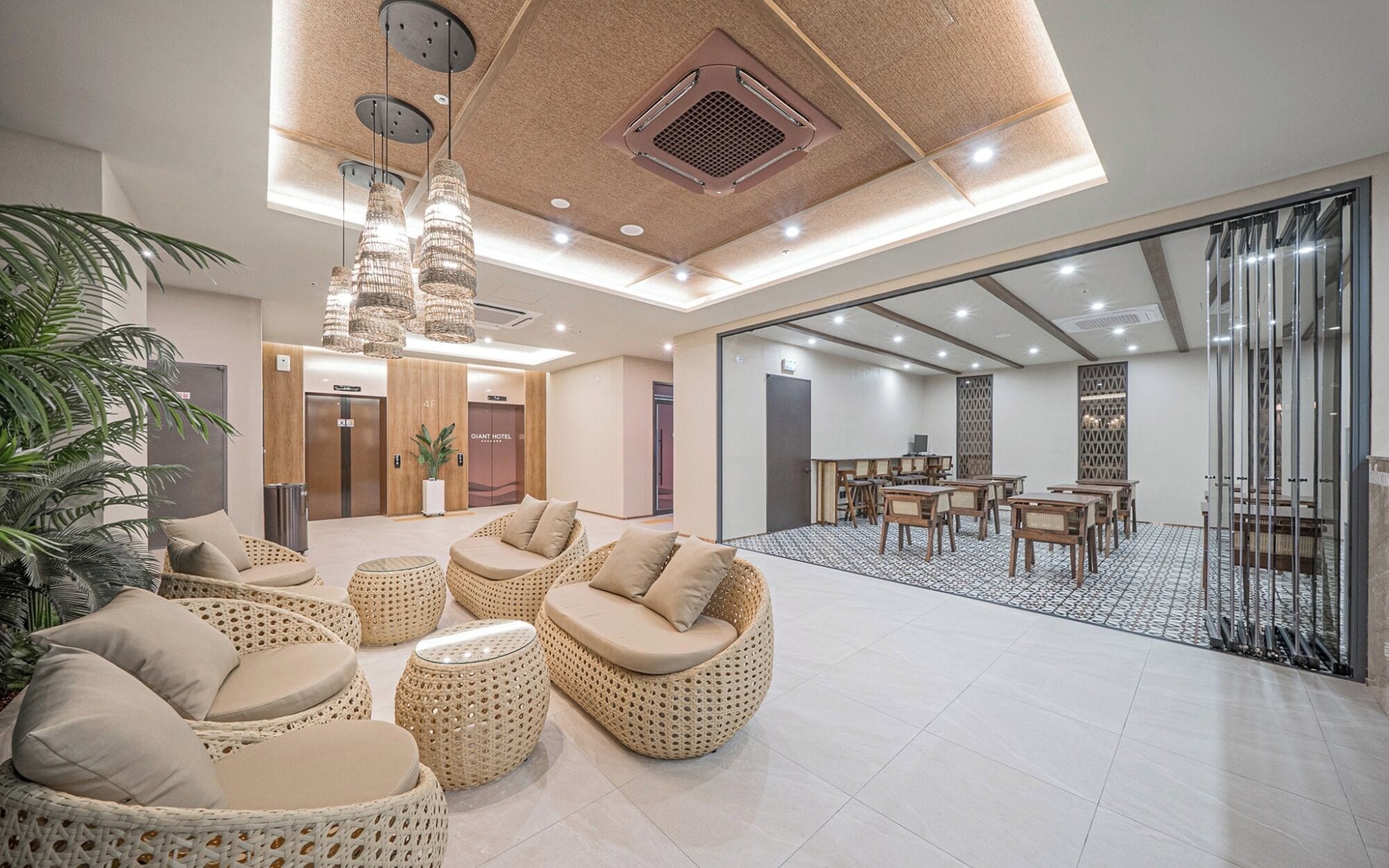 A spacious lobby with wicker furniture, a large seating area, and a view into a dining area.