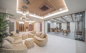 Un vestíbulo amplio con mobiliario de mimbre, un amplio espacio para sentarse y vistas a un comedor.