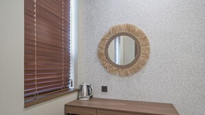 A bathroom with a wooden vanity, a round mirror with a fringe frame, and a window with blinds. - Giant Hotel (Daegu)