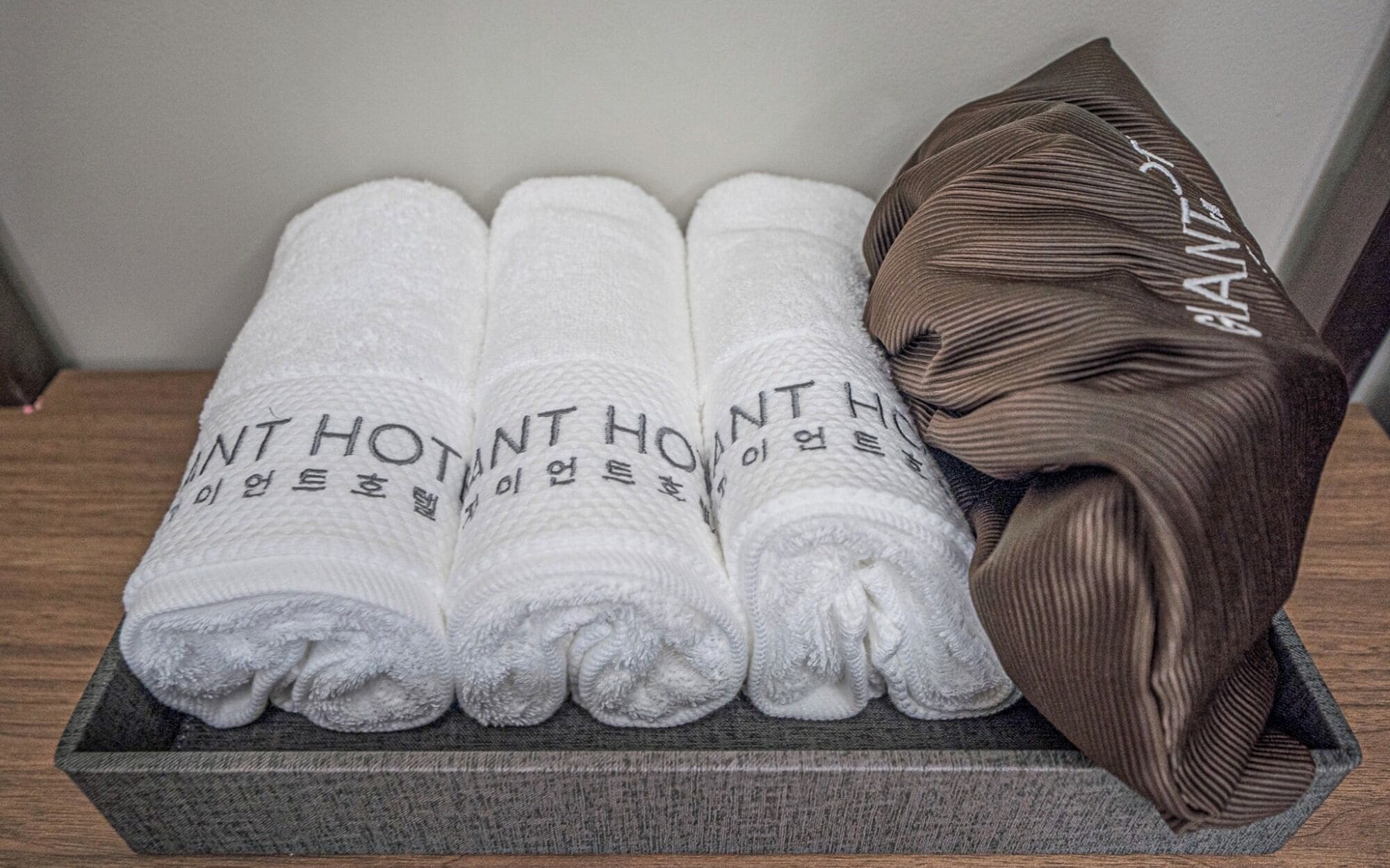 A set of neatly folded towels with Korean text, placed in a wooden tray.