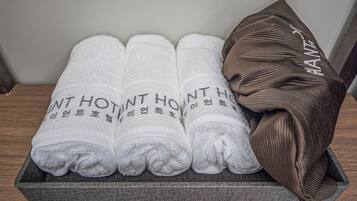 A set of neatly folded towels with Korean text, placed in a wooden tray.