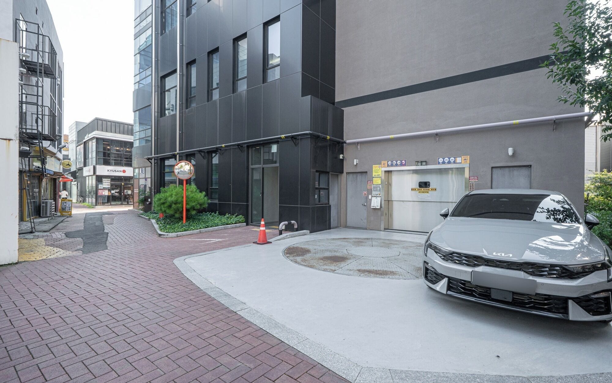 A modern building with a parking area and a white car parked in front.